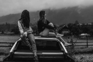 teen girls sitting on hood of car