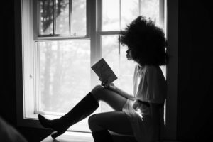 woman reading on window sill